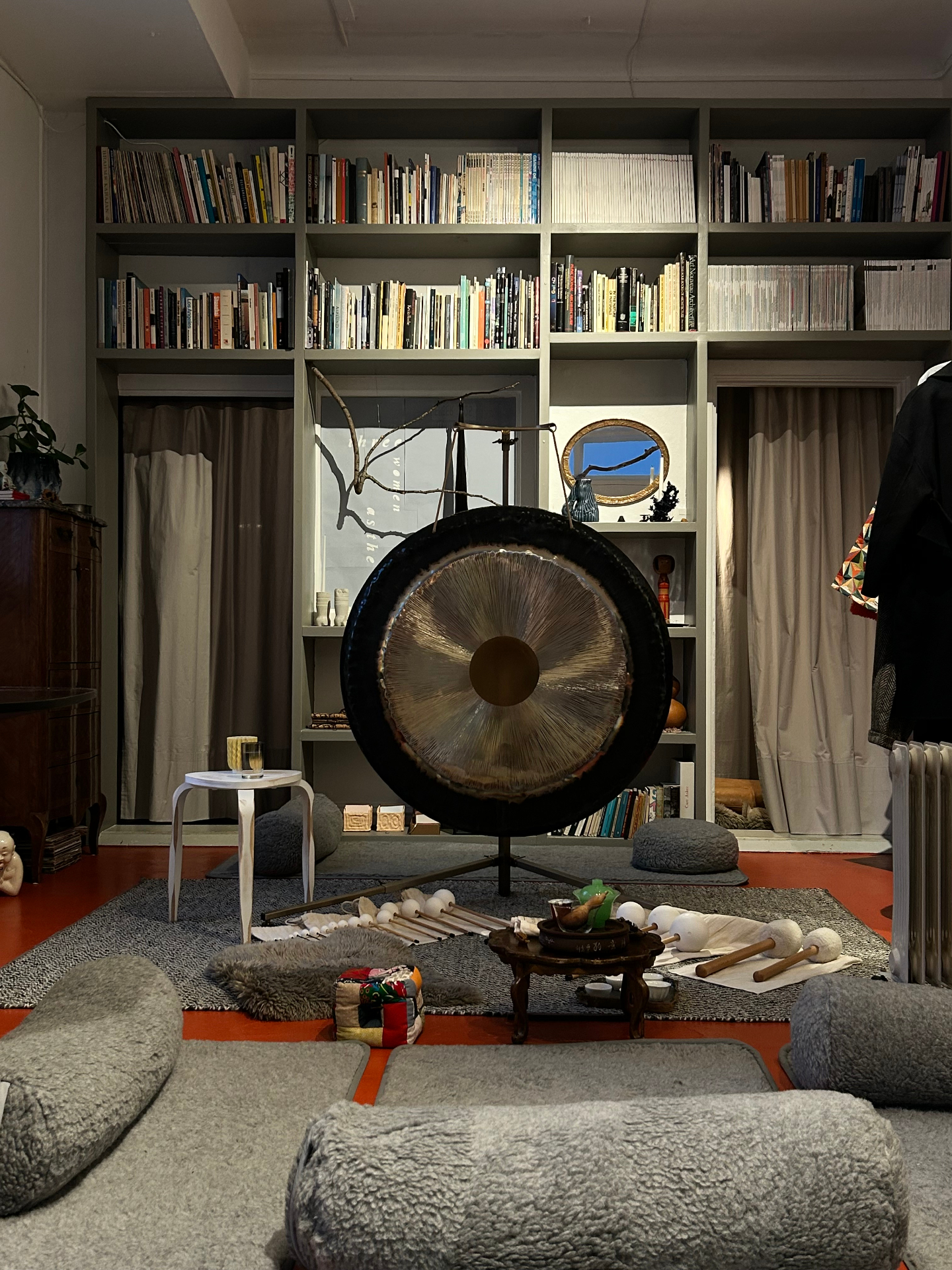 Large bronze gong on stand inside a library lined with art and architecture books